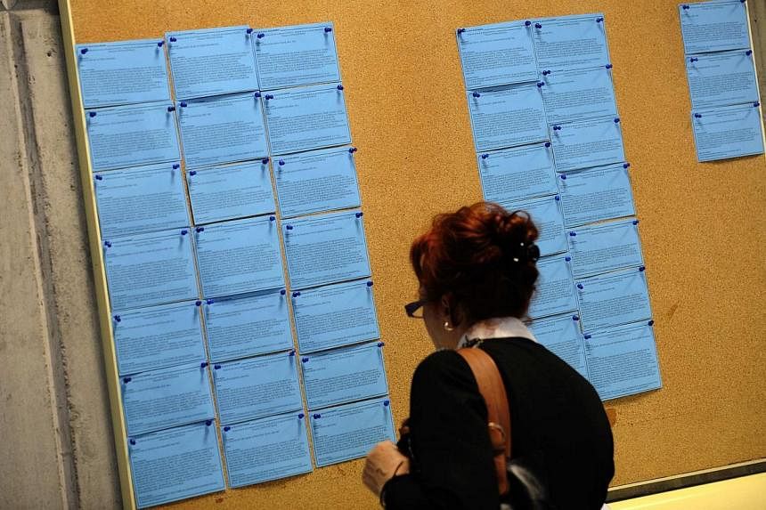 A woman looks at a board with job listings in an unemployment office in Gijon, northern Spain on April 30, 2014. -- PHOTO: REUTERS