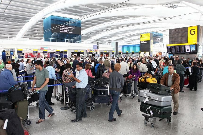 Passengers line up for information at Terminal 5 at Heathrow Airport in London, UK, on Thursday, April 15, 2010. British police arrested two people at Heathrow airport on Saturday on suspicion of “terrorism" -related activities in Syria, they said.