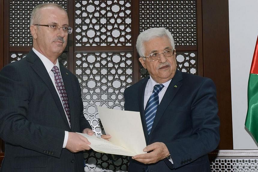 A handout picture released by the Palestinian president's office shows Palestinian president Mahmud Abbas (right) meeting with Palestinian premier Rami Hamdallah in the West Bank city of Ramallah to hand over an agreement for Hamdallah to head the co