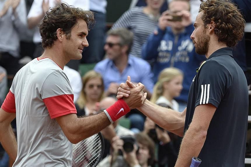 Latvia's Ernests Gulbis (right) shakes hands with Switzerland's Roger Federer at the end of their French tennis Open round of 16 match against at the Roland Garros stadium in Paris on June 1, 2014. Federer crashed to his earliest French Open defeat s