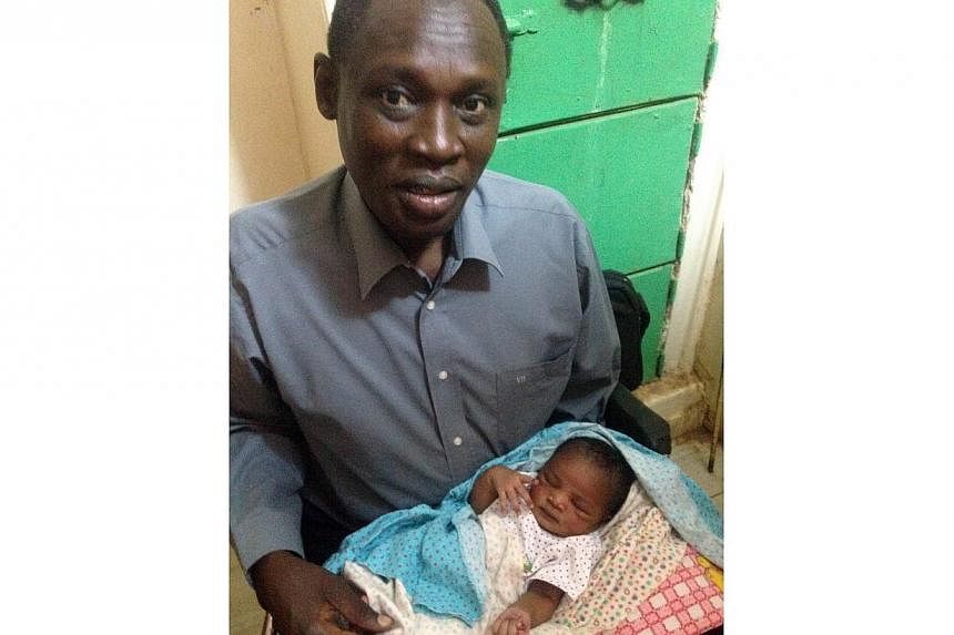 A handout picture taken on May 28, 2014, and released by the family on May 30, shows Daniel Wani, a US citizen originally from South Sudan, carrying his newborn daughter Maya at the womens prison in Khartoum's twin city of Omdurman. -- PHOTO: AFP