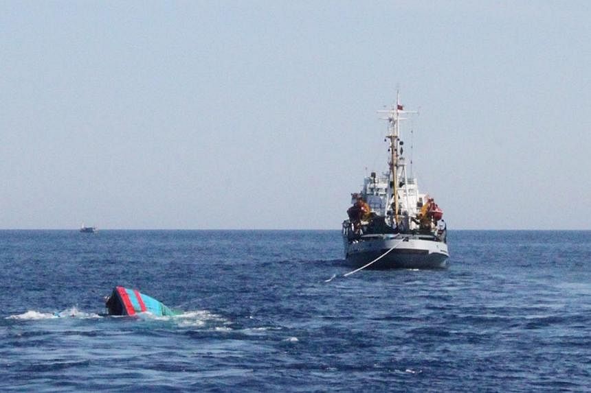 A Vietnamese sinking boat (left) which was rammed and then sunk by Chinese vessels near disputed Paracels Islands, is seen near a Marine Guard ship (right) at Ly Son island of Vietnam's central Quang Ngai province on May 29, 2014. -- PHOTO: REUTERS