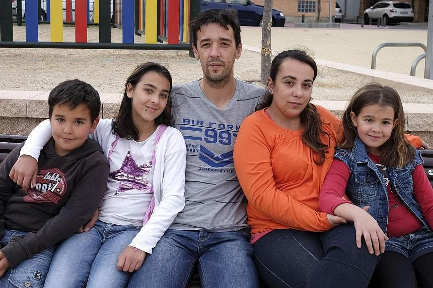 Patricia Martin (second, right) pose wtih her husband (centre) and children on a bench near their home in Vallecas, a neighborhood of Madrid on May 21, 2014. -- PHOTO: AFP