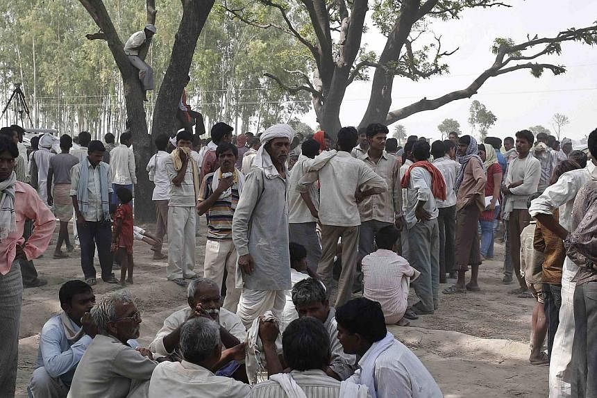 Onlookers stand at the site where two teenage girls, who were raped, were hanged from a tree at Budaun district in the northern Indian state of Uttar Pradesh on May 31, 2014. -- PHOTO: REUTERS