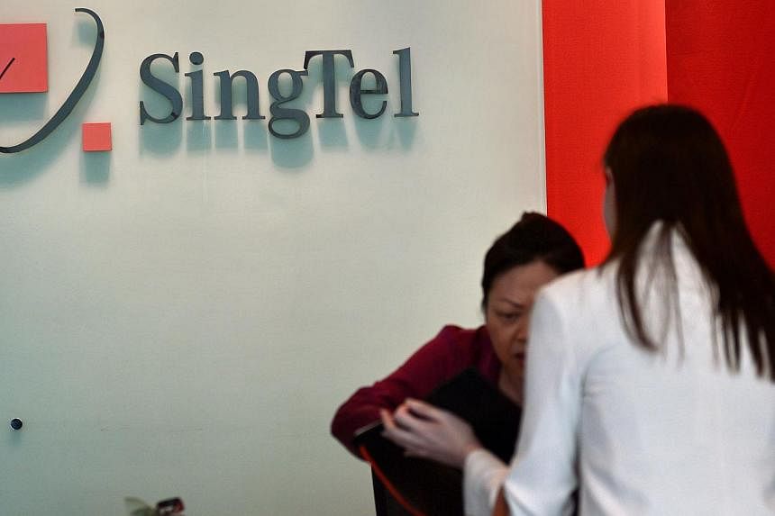 A receptionist attends to a customer at the SingTel com centre building in Singapore on May 15, 2014. -- PHOTO: AFP