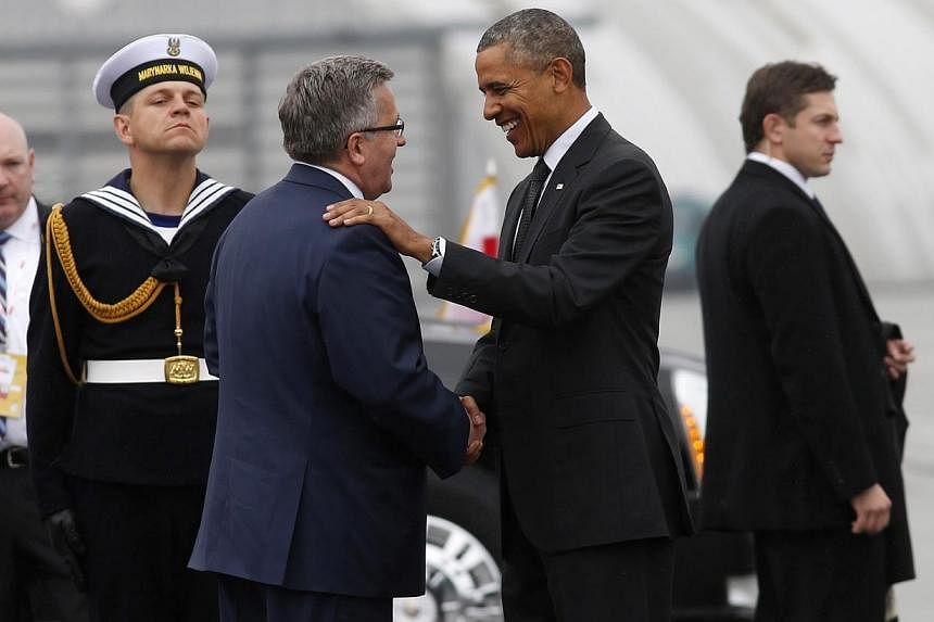 US President Barack Obama (centre, right) is greeted by Poland's President Bronislaw Komorowski upon his arrival in Warsaw on June 3, 2014.&nbsp;Mr Obama launched a European tour on Tuesday, June 3, 2014, shaped by the escalating separatist insurgenc