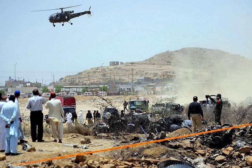 Pakistani security officials inspect the site where a Pakistan air force fighter plane crashed at a bus terminal on the outskirts of Karachi on June 3, 2014.&nbsp;A Pakistan air force fighter plane crashed at a bus terminal on the outskirts of Karach