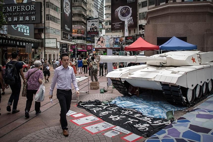 Pedestrians walk past a tank replica displayed to symbolise China's June 4, 1989 Tiananmen military crackdown in Hong Kong on June 3, 2014.&nbsp;Taiwan on Tuesday, June 3, 2014, urged China to face up to history and protect the rights of dissidents o