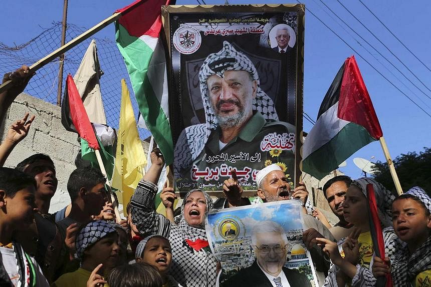 Palestinians hold pictures of late Palestinian leader Yasser Arafat (top) and Palestinian President Mahmoud Abbas as they celebrate the announcement of the unity government, in Khan Younis in the southern Gaza Strip on June 2, 2014. -- PHOTO: REUTERS