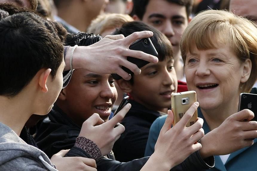Pupils take mobile phone photos of German Chancellor Angela Merkel, as she arrives for a visit at Robert-Jungk Europe high school as part of the Europe-Project Day, in Berlin on March 31, 2014 .&nbsp;Germany's federal prosecutor said on Wednesday, Ju