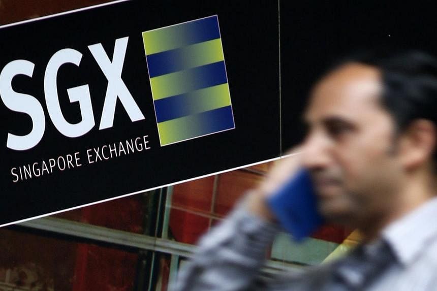 An office worker walks past a logo of the Singapore Stock Exchange (SGX) on April 23, 2014. -- PHOTO: REUTERS