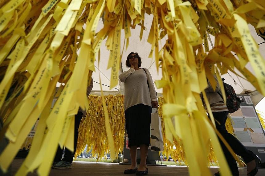 A woman reads messages on yellow ribbons dedicated to dead and missing passengers of the sunken ferry Sewol at Seoul City Hall Plaza in Seoul on May 19, 2014. -- PHOTO: REUTERS