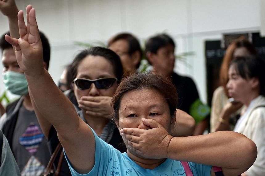 An anti-coup protester flashing the three-finger salute borrowed from the Hunger Games movies during a gathering at a shopping mall, which was broken up by security forces of Thailand's ruling junta. -- PHOTO: AFP