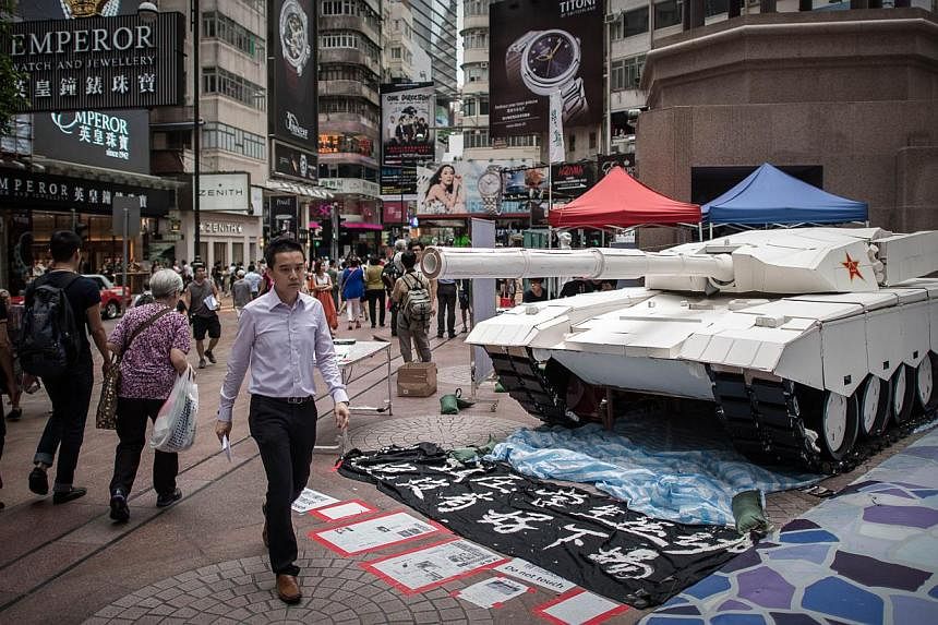 Pedestrians walk past a tank replica displayed to symbolise China's June 4, 1989 Tiananmen military crackdown in Hong Kong on June 3, 2014. -- PHOTO: AFP