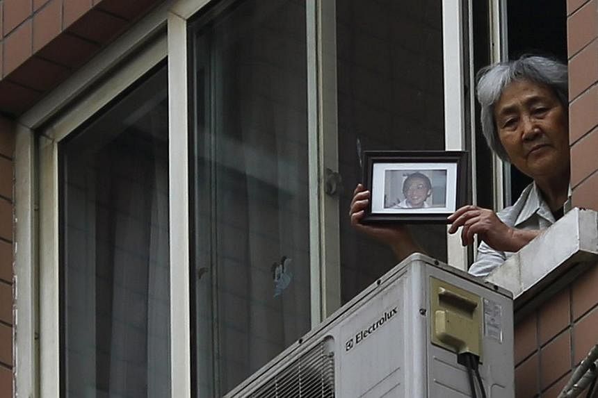 Zhang Xianling, whose son Wang Nan was killed by soldiers at the Tiananmen Square in 1989, holds his picture after journalists were turned away, at the window of her home in Beijing, on April 24, 2014. -- PHOTO: REUTERS