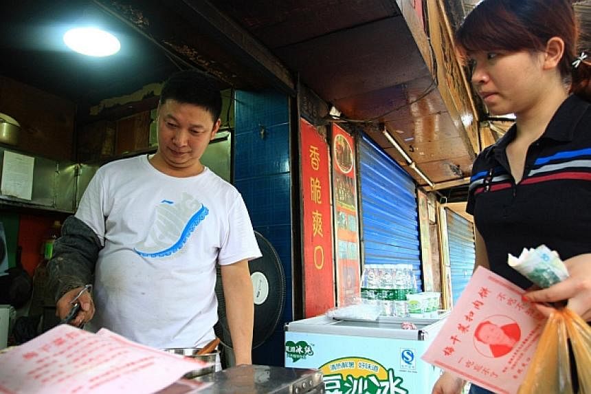 Meat-pie vendor Shao Jianhua (left), who looks like Chinese President Xi Jinping, works at his stall in Changsha, central China's Hunan province on June 5, 2014. -- PHOTO: AFP