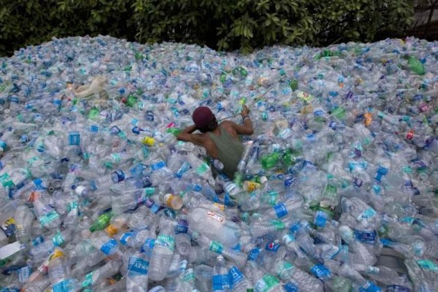 A worker uses a rope to move through a pile of empty plastic bottles at a recycling workshop in Mumbai on June 5, 2014. According to the United Nations Environment Programme website, World Environment Day is celebrated annually on June 5 to raise glo
