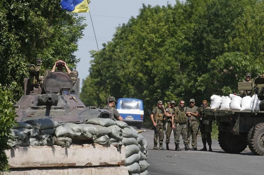 Ukrainian servicemen stand guard at a checkpoint near the town of Amvrosievka, in Donetsk region on June 5, 2014.&nbsp;Thousands of Ukrainians are flooding across the border into Russia to escape the armed conflict, Russian Prime Minister Dmitry Medv