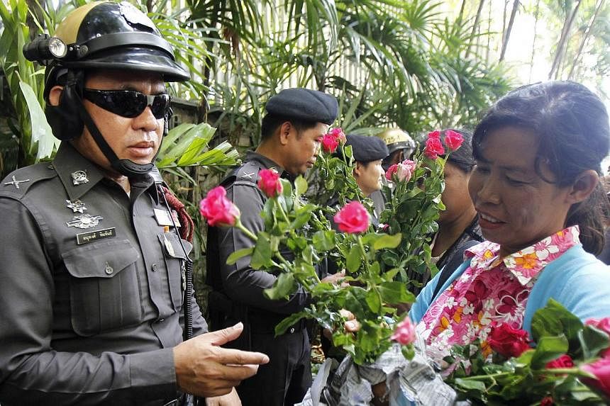 A military rule supporter hands roses to policemen guarding the Australian embassy in Bangkok June 4, 2014. -- PHOTO: REUTERS