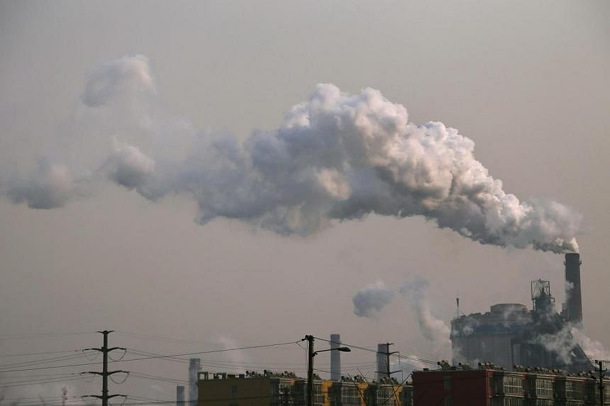 Smoke rises from a chimney of a steel plant next to residential buildings on a hazy day in Fengnan district of Tangshan, Hebei province on Feb 18, 2014. -- PHOTO: REUTERS