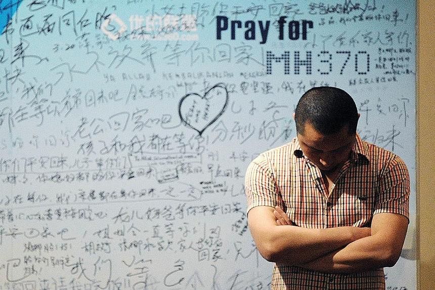 A man stands in front of a billboard in support of missing Malaysia Airlines flight MH370 as Chinese relatives of passengers on the missing Malaysia Airlines flight MH370 have a meeting at the Metro Park Hotel in Beijing on April 23, 2014.&nbsp;It is