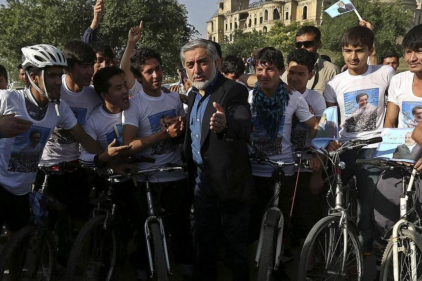 Afghan presidential candidate Abdullah Abdullah talks with a group of cyclists during the second round of the presidential candidate election campaign in Kabul on June 6, 2014.Two bombs exploded outside a hotel in western Kabul where presidential fro