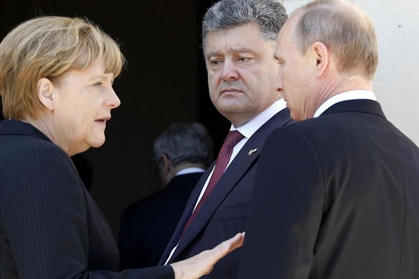German Chancellor Angela Merkel (left), Ukrainian President-elect Petro Poroshenko and Russian President Vladimir Putin (right) speak following a group photo of world leaders attending the D-Day 70th Anniversary ceremonies at Chateau de Benouville in