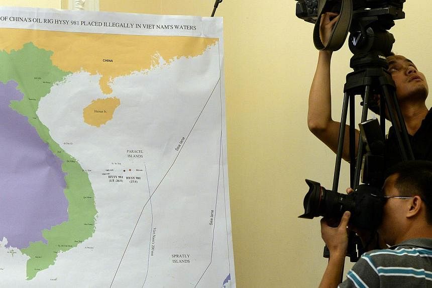 A photographer takes picture of a map showing the position of the Chinese oil rig in the disputed waters at the South China Sea during a press conference in Hanoi on June 5, 2014 held by Vietnamese Foreign Ministry accusing Chinese ships of attacking