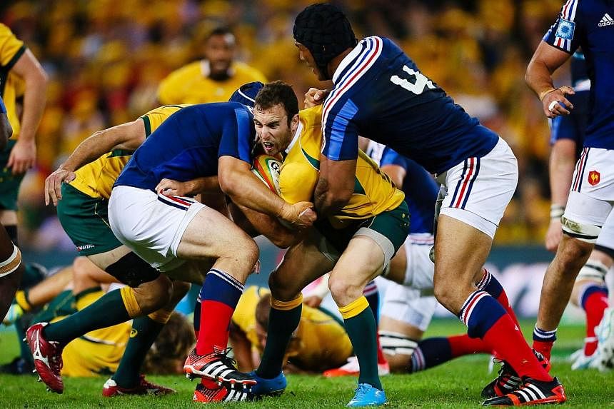 Australian halfback Nic White (centre) is tackled by France's Damien Chouly (left) during the first rugby union test match at Suncorp Stadium in Brisbane on June 7, 2014. -- PHOTO: AFP