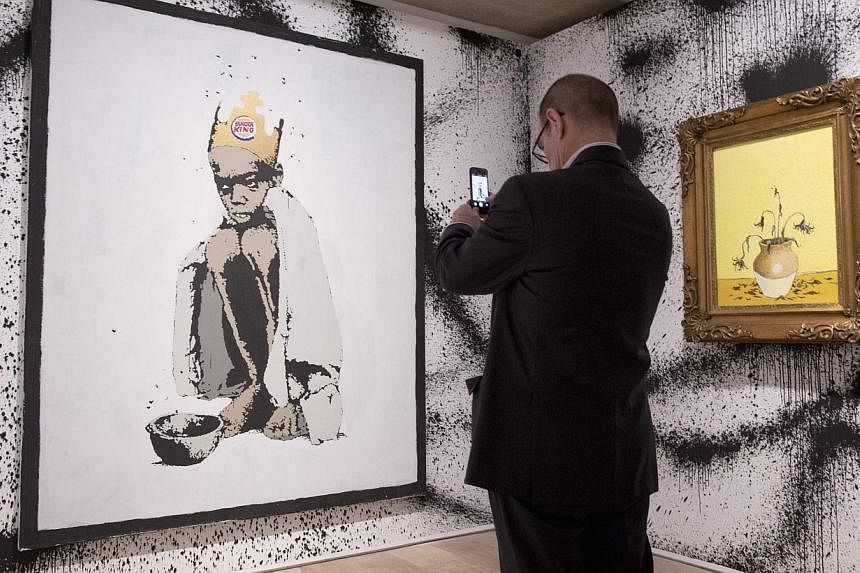 A man photographs the work Burger King at the Banksy:&nbsp;The Unauthorised Retrospective exhibition at Sotheby's S2 Gallery in London on June 6, 2014. -- PHOTO: REUTERS