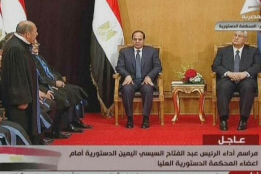 An image grab taken from Egyptian state TV shows ex-army chief and newly elected Egyptian President Abdel Fattah al-Sisi (center) sitting next to interim president Adly Mansour (right), during Sisi' swearing in ceremony, on June 7, 2014, in Cairo.&nb