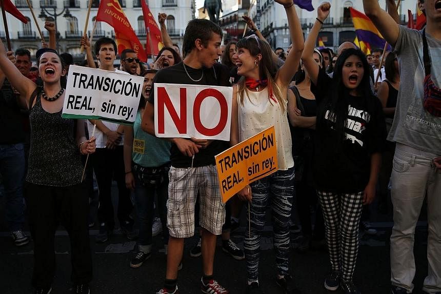 People shout slogans against the monarchy as they hold placards that read "Real transition, without a king" at Madrid's landmark Puerta del Sol square during an anti-monarchy demonstration June 7, 2014.&nbsp;The majority of Spaniards want a referendu