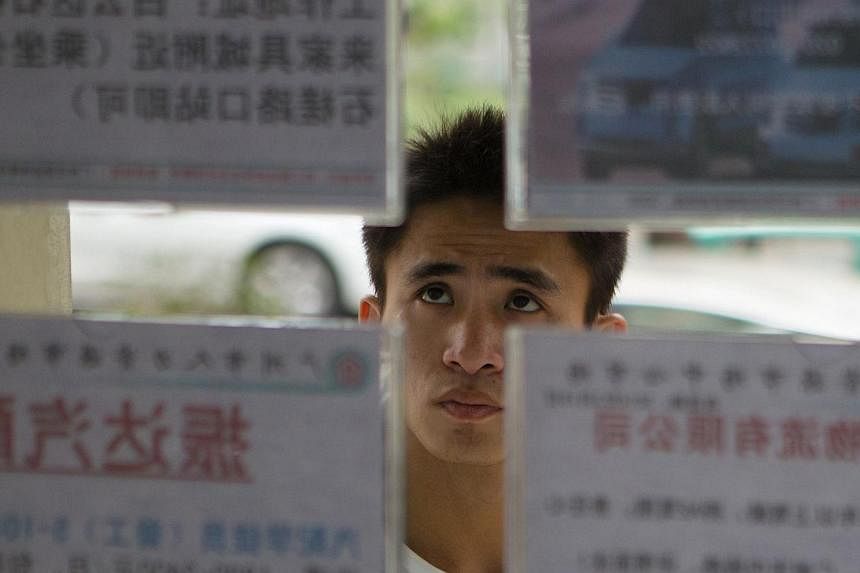 A job seeker looks at recruitment advertisements at a labour market in Guangzhou, Guangdong province on Feb 24, 2014. A record 7.27 million graduates - equivalent to the entire population of Hong Kong - will enter the job market this year; a market t