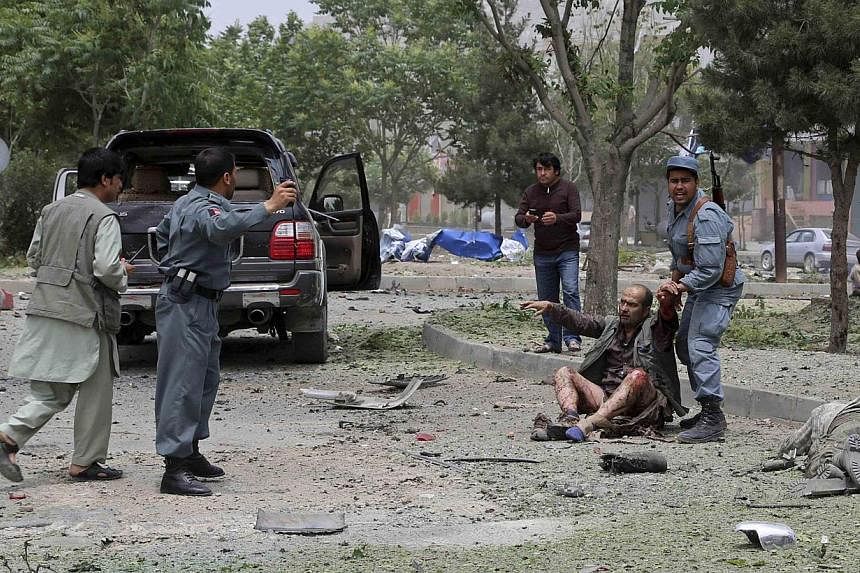 An Afghan policeman helps a wounded man after a suicide bomb attack in Kabul in this on June 6, 2014, picture provided by Abdullah Abdullah's campaign office.&nbsp;Security is being ramped up so the two candidates in Afghanistan's presidential electi