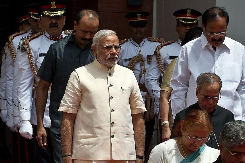 Indian President Pranab Mukherjee (2nd right, in black) arrives with Indian Prime Minster Narendra Modi (front left, in tan) to address the joint session of Parliament in New Delhi on June 9, 2014.&nbsp;India's new government pledged on Monday to mak