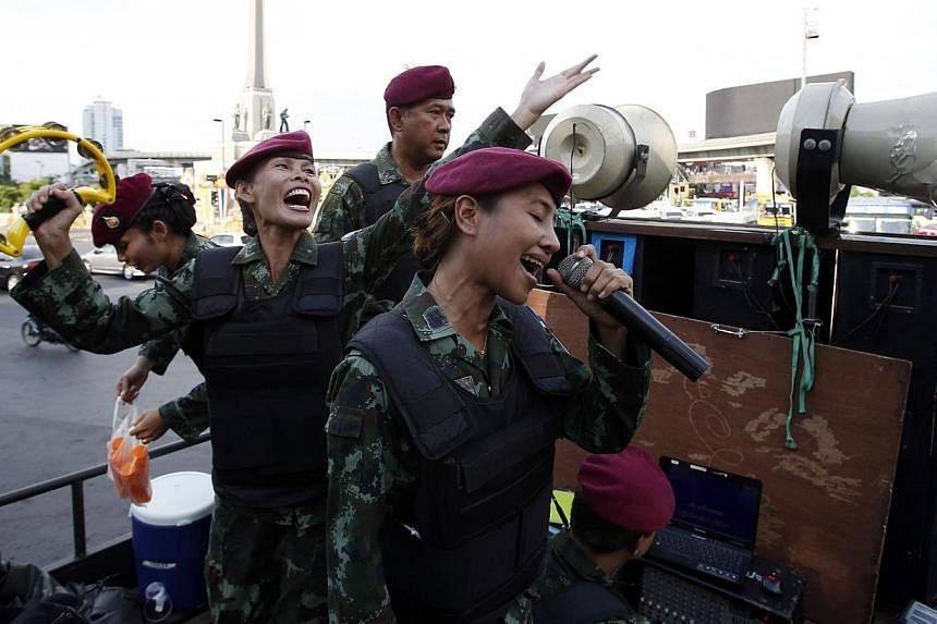 Female Thai soldiers sing patriotic songs on a military truck as soldiers and police take positions to prevent demonstrations against military rule at Victory Monument in Bangkok on June 3, 2014.&nbsp;A ballad penned by a coup-making army chief promi