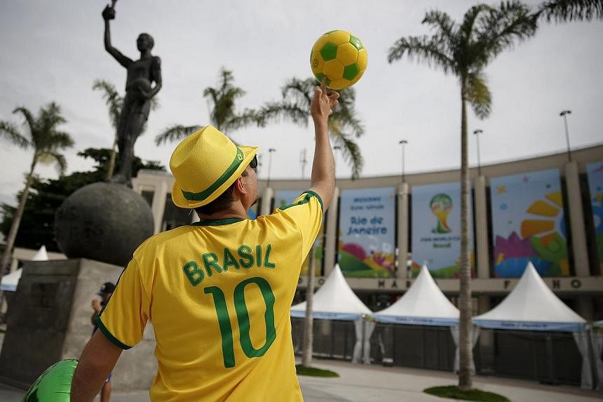 A street busker spinning a ball in Rio de Janeiro ahead of the World Cup. While the party is in full swing in Brazil, stockbrokers in Singapore are expecting commissions to drop by as much as 50 per cent during the World Cup period. -- PHOTO: REUTERS