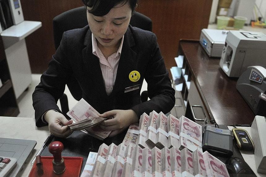 A clerk counts 100 Chinese yuan banknotes at a branch of China Merchants Bank in Hefei, Anhui province, in this file photo. China's central bank announced details Monday of a plan that reduces the amount of money rural banks must keep in reserve, a m
