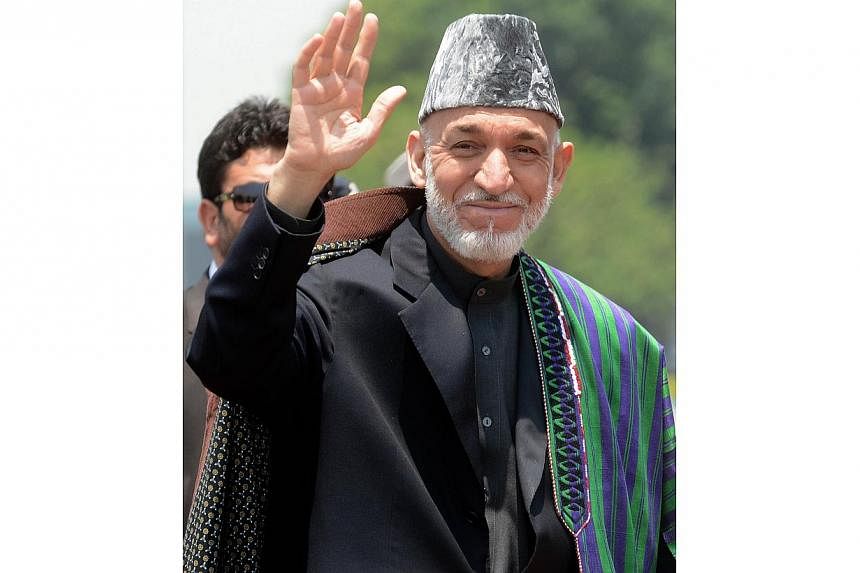 Afghan President Hamid Karzai waves on his arrival at New Delhi airport on May 26, 2014. Mr Karzai is due to step down in the coming weeks after Saturday's run-off election, paving the way for Afghanistan's first democratic transfer of power. -- PHOT