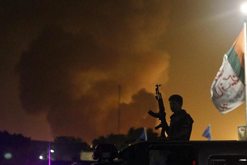 A policeman with a gun stands on a vehicle as smoke bellows from Jinnah International airport in Karachi on June 9, 2014. -- PHOTO: REUTERS