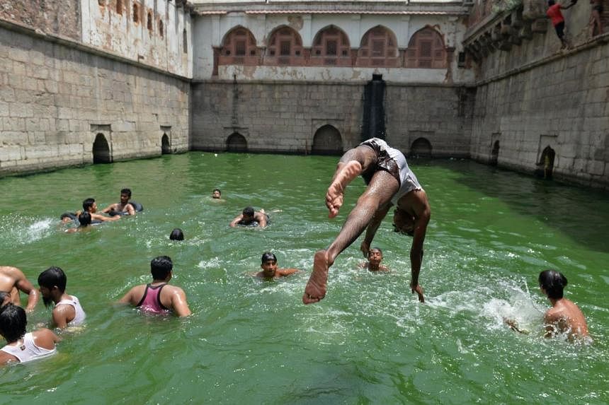 An Indian youth jumps into the water at the Nizamuddin Baoli, a stepwell built circa 1321-1322 that holds water from an underground spring, near the dargah (shrine) of Hazrat Nizamuddin Auliya in New Delhi on June 8, 2014.&nbsp;Delhi's government is 