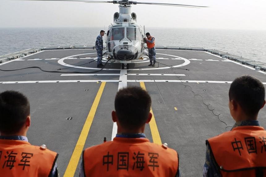 Chinese naval sailors look on as a helicopter gets ready to take off from Chinese naval frigate Linyi during multi-country maritime joint exercises off the coast in Qingdao, Shandong province on April 23, 2014. China has confirmed it will participate