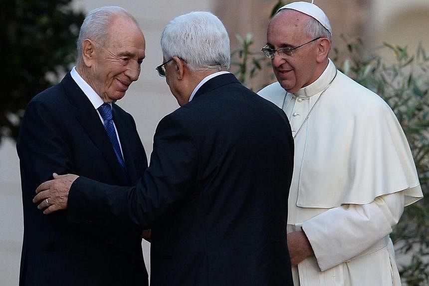 Israeli President Shimon Peres (left) shakes hands with Palestinian leader Mahmud Abbas as Pope Francis looks on after they plant an olive tree in the Vatican's gardens following a joint peace prayer at the Vatican on June 8, 2014. -- PHOTO: AFP