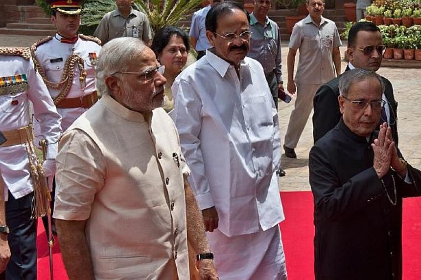 Indian President Pranab Mukherjee (right) gestures a greeting as he arrives with Indian Prime Minster Narendra Modi (left) to address the joint session of Parliament in New Delhi on June 9, 2014.&nbsp;India's new government will engage energetically 