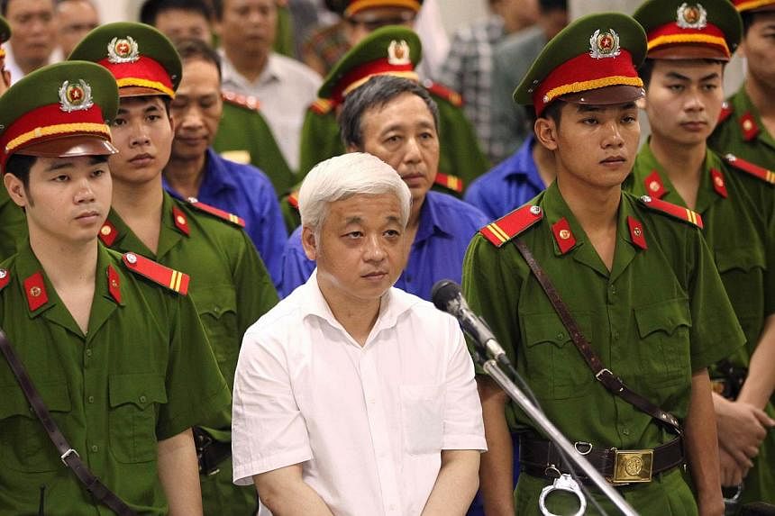 Former Vietnamese banking tycoon Nguyen Duc Kien (C), 50, stands listening to the verdict read at the Hanoi People's Court on June 9, 2014.&nbsp;A Vietnamese court on Monday sentenced a disgraced banking tycoon to 30 years in jail over a multi-millio