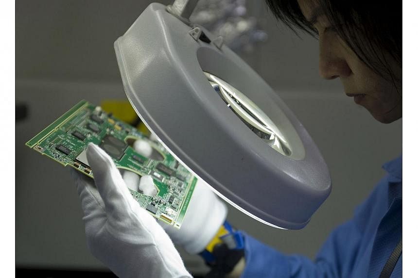 A worker inspects a printed circuit board on the assembly line at the Venture Corp. factory in Singapore, on Monday, Dec 15, 2008. -- PHOTO: BLOOMBERG
