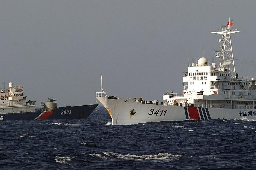 A Vietnamese Coast Guard ship (left) is challenged by a China Coast Guard ship near the site of a Chinese drilling oil rig (right, background) being installed in the disputed waters in the South China Sea off Vietnam's central coast on May 14, 2014.&