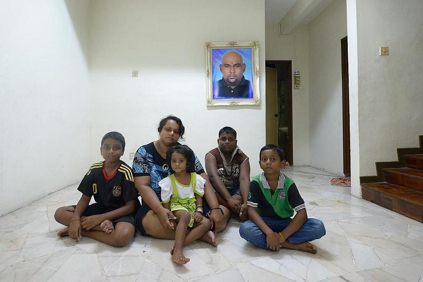 Madam Pusparani Mohan, 34, with her children (from left) Dharmaa, 10, Thurgashini, two, Sarveswaran, 11, and Mageswaran, seven. In the background is a portrait of her late husband Chandra Mogan Panjanathan, who was killed after he was hit by a taxi o