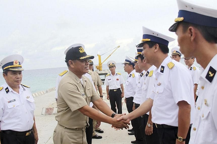 A Filipino naval officer (second from left) being greeted by Vietnamese naval officers upon his arrival on the Vietnam-held Song Tu Tay or South-west Cay island of the disputed Spratly Islands in the South China Sea on June 8, 2014. Vietnamese and Ph