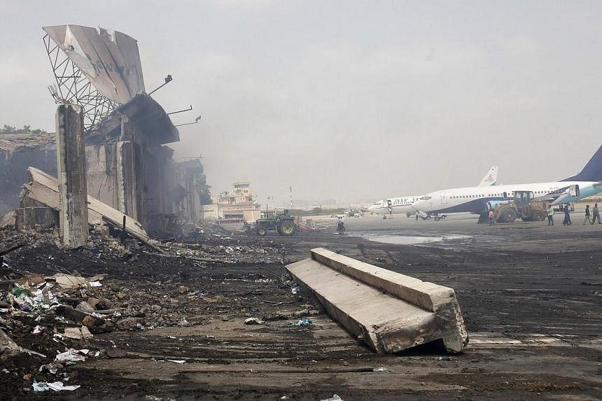 Planes are seen near a section of a damaged building (L) at Jinnah International Airport, after Sunday's attack by Taliban militants, in Karachi on June 10, 2014.&nbsp;Taleban gunmen attacked a security post outside Pakistan's Karachi Airport on Tues